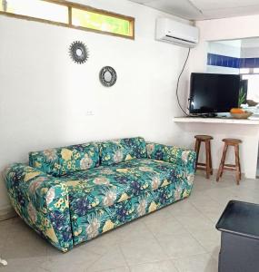 a living room with a couch and a tv at Hostal CORALES in Tolú