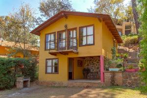 a yellow house with a balcony on top of it at Cabañas Sofía y Andrea in Mazamitla