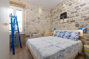 sypialnia z niebieskim łóżkiem i kamienną ścianą w obiekcie Apartments Kaja w Trogirze