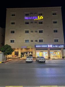 two cars parked in a parking lot in front of a hotel at ذرا الماضي للشقق المخدومة 1 in Al Bukayriyah