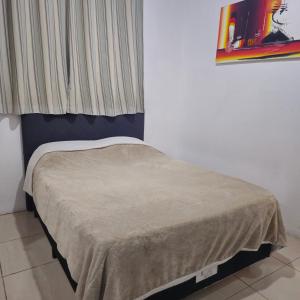 a small bed in a room with a window at Kyrie Canoinhas Hotel in Canoinhas