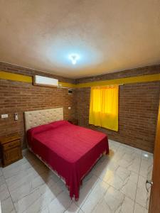 a bedroom with a red bed with a yellow curtain at La bendicion in Villa Cura Brochero