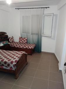 a bedroom with two beds and a window at Appartement F3 aich el vez in Bejaïa