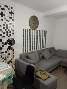 a living room with a couch and a clock on the wall at Appartement F3 aich el vez in Bejaïa