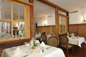 a restaurant with white tables and chairs and windows at Auberge de la Croix Blanche in Villarepos