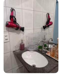 a bathroom sink with a red blow dryer on the wall at Apartamento hostel para Mulheres in Vila Velha