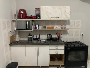 a small kitchen with a sink and a stove at Apartamento hostel para Mulheres in Vila Velha