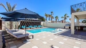 a pool with chairs and an umbrella next to a swimming pool at Paz Del Mar 30 in Puerto Peñasco