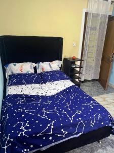 a bed with a blue comforter with stars on it at Appartement Climatisé et Résidence Sécurisée Kribi in Kribi