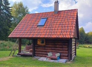 a small log cabin with an orange roof at Tammiku Saunamaja & Bubble House in Röösa