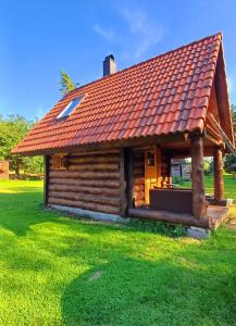 a log cabin with a red roof on a green field at Tammiku Saunamaja & Bubble House in Röösa