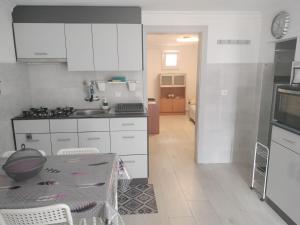 a kitchen with white cabinets and a table with chairs at Casa São Miguel T2 in Serpa