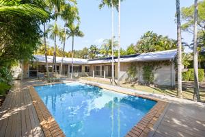 una piscina frente a una casa con palmeras en Modern Oasis in Noosa Heads, en Noosa Heads