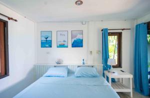 a bedroom with a blue bed and a window at Sunset Dream Beach Front House in Thong Sala
