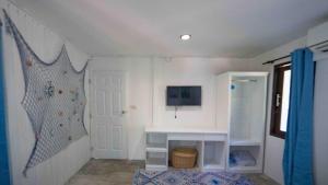 a room with a white wall with a door and a tv at Sunset Dream Beach Front House in Thong Sala