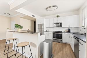 a kitchen with white cabinets and a counter with stools at Stylish 2BR Condo with Amenities Near Six Flags in Santa Clarita