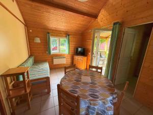 a dining room with a table and a couch in a cabin at Chalet Édelweiss 35 en lisière de forêt, calme et nature - FR-1-583-444 in Mélisey