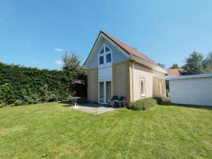 a small house with two chairs in a yard at Cozy Beach House Beautiful Water View, WiFi & Parking in Kamperland