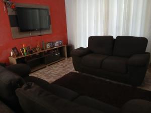 a living room with a couch and a flat screen tv at Casa Festa do Peão Barretos in Barretos