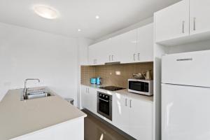 a kitchen with white cabinets and a white refrigerator at Soho 203 in Geelong +10 photos