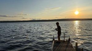 a man fishing on a dock on a lake at La Brise O-Lac in Sherbrooke