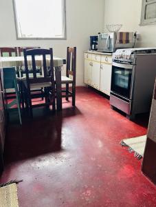 une cuisine avec un sol rouge avec une table et une cuisinière dans l'établissement Casa mar, à Angra dos Reis