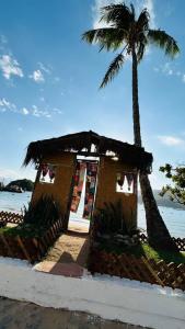 une petite maison avec un palmier à côté de l'océan dans l'établissement Casa mar, à Angra dos Reis