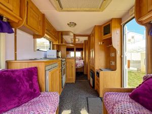 a kitchen with wooden cabinets and purple cushions in a caravan at Relax by the Sea Camping in Costinesti