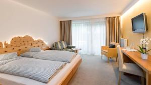 a hotel room with a large bed and a desk at Hotel Stefaner in Tires