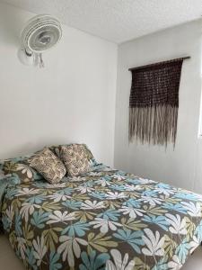 a bedroom with a bed with a floral bedspread and a fan at apulo jacana del lago in Apulo