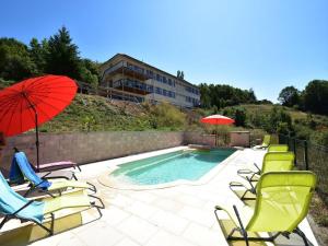 a group of chairs and umbrellas next to a pool at Apartment in Cuzy with Heated Pool in Cuzy