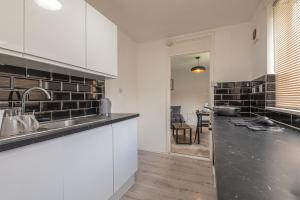 a kitchen with white cabinets and a black counter top at Luxus Flat Near Leeds City Centre in Central Station +8 photos