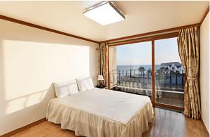 a bedroom with a bed and a large window at Geogwipo Jeju Castle in Hogŭn-ni