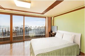 a bedroom with a bed and a large window at Geogwipo Jeju Castle in Hogŭn-ni