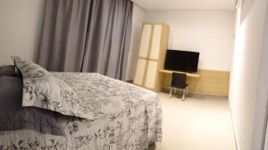 a bedroom with a bed and a flat screen tv at Apartamentos chácara com café da manhã incluso in Petrolina