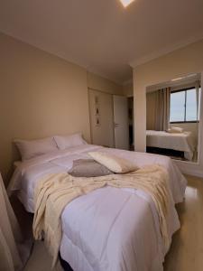 a bedroom with two beds with white sheets and a window at Apê com vista para o mar e clima animado in Vitória