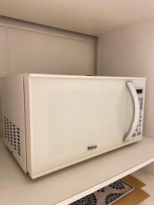 a white microwave sitting on top of a shelf at Apê com vista para o mar e clima animado in Vitória