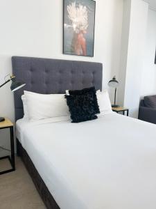a bedroom with a large white bed with a black headboard at 806 Deluxe Delight Concert Hall Studio in Perth