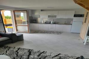a large kitchen with white cabinets and a couch at Holiday home, 3 bedrooms, fishing pond, sauna in Wodnica