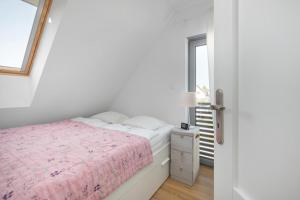 a white bedroom with a bed and a window at Holiday home, 3 bedrooms, private garden in Trzęsacz