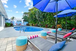 a pool with chairs and an umbrella next to a pool at 4br Home W Guest Suite Pool Near Pga & Beach in Palm Beach Gardens