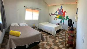 a bedroom with two beds and a painting on the wall at Casa Raizes Pousada in Ilha Cotejuba