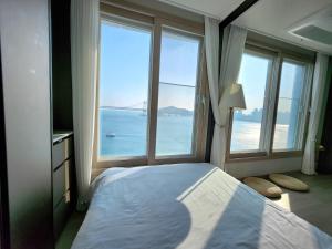 ein Schlafzimmer mit großem Fenster mit Blick auf das Meer in der Unterkunft Busan #Gwanganri #Full Ocean #Healing in Busan