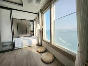 ein Schlafzimmer mit einem Bett und einem großen Fenster in der Unterkunft Busan #Gwanganri #Full Ocean #Healing in Busan
