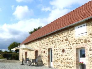 a brick building with a table and an umbrella at Maison rénovée pour couple au cœur d'une ferme avec SPA - FR-1-489-579 in Cressanges