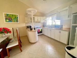 a kitchen with white cabinets and a table and a counter at Villa Española in Sosúa
