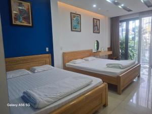 two beds in a bedroom with blue walls at Khoi Nguon in Danang