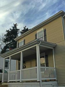 a yellow house with a porch with a white railing at Walk To Hospital, Heart Of Cville, Fenced Backyard in Charlottesville