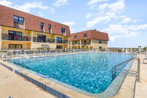 a swimming pool at a resort with chairs and a building at Beachfront with heated pool, 60 seconds to beach in Cocoa Beach
