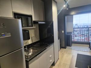 a kitchen with a sink and a refrigerator and a window at Studio Modelo -Tucuruvi-SP in Sao Paulo